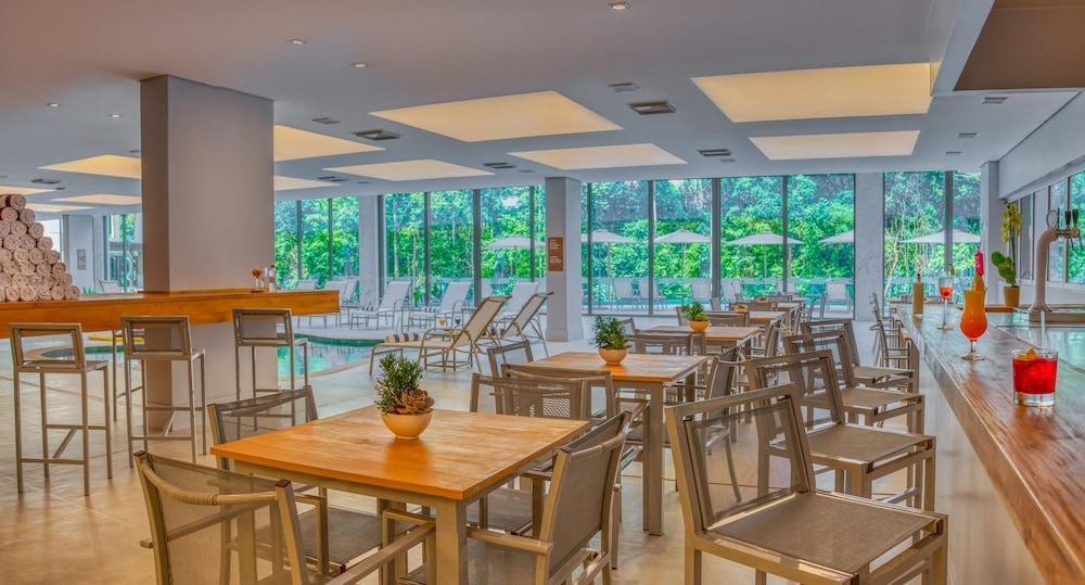 Wyndham Gramado Termas Resort & Spa Exterior foto The image shows a modern, spacious indoor restaurant or café area. It features wooden tables with metal frames and chairs placed throughout the space. There is a minimalist bar area on one side. Large windows allow natural light to fill the room and 