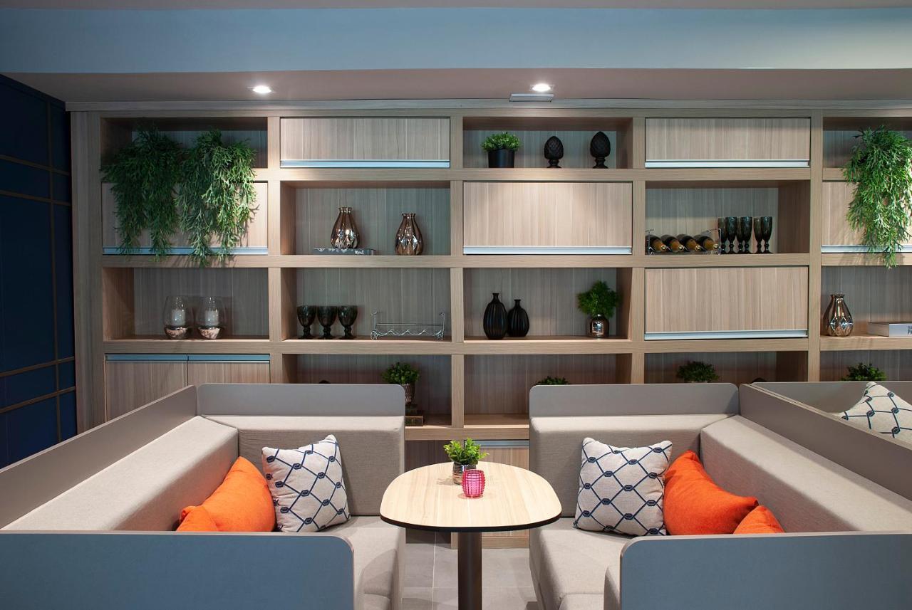 Wyndham Gramado Termas Resort & Spa Exterior foto The photo shows a modern seating area featuring two low, comfortable sofas arranged in an L-shape. The sofas are upholstered in a light grey fabric with decorative cushions in orange and a patterned design. In the center, there's a small round table 