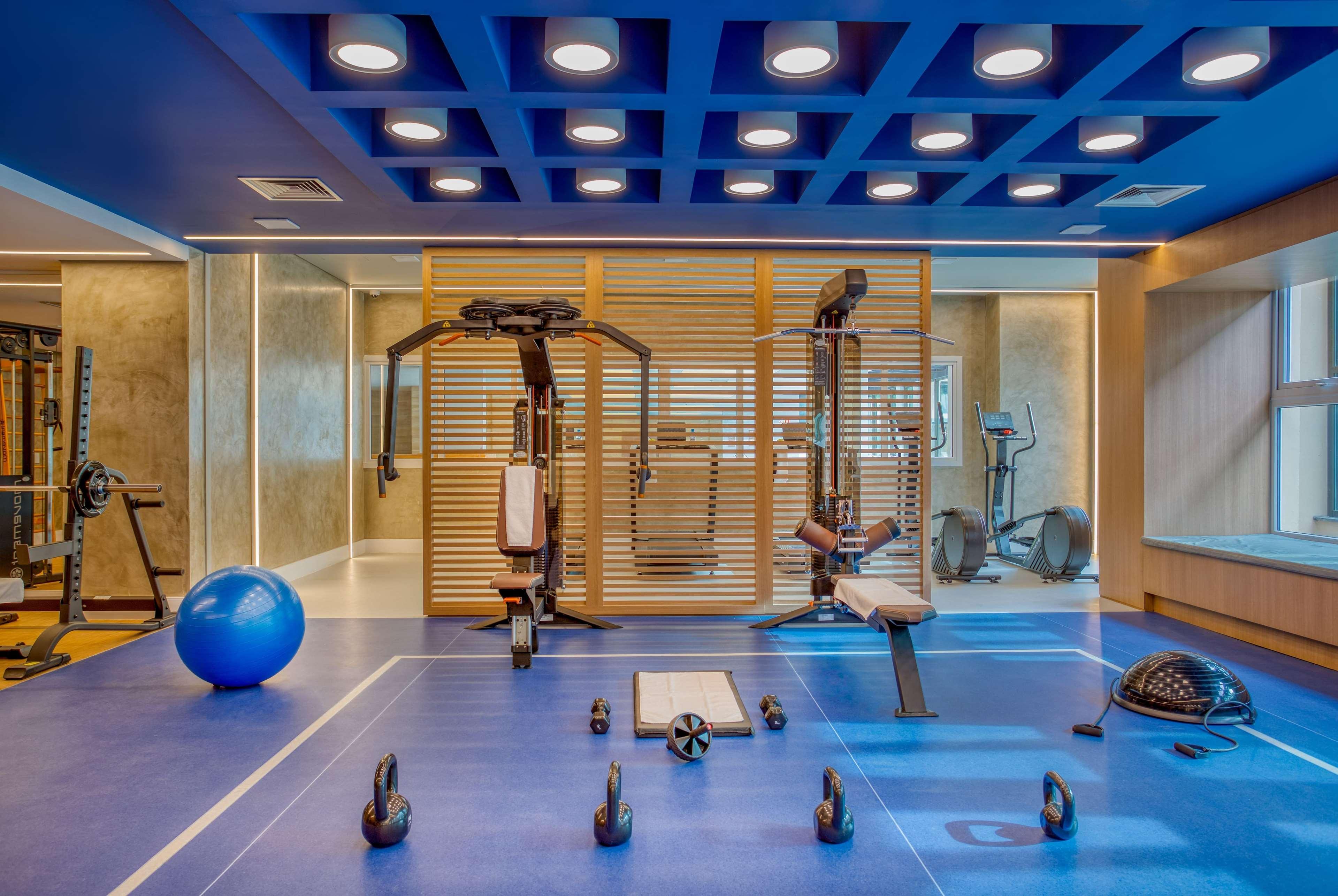 Wyndham Gramado Termas Resort & Spa Exterior foto The photo shows a modern gym interior. It features various exercise equipment, including a multi-station weight machine, a bench, and a stability ball. The floor is covered with blue mats, and there are also several kettlebells and an exercise roller