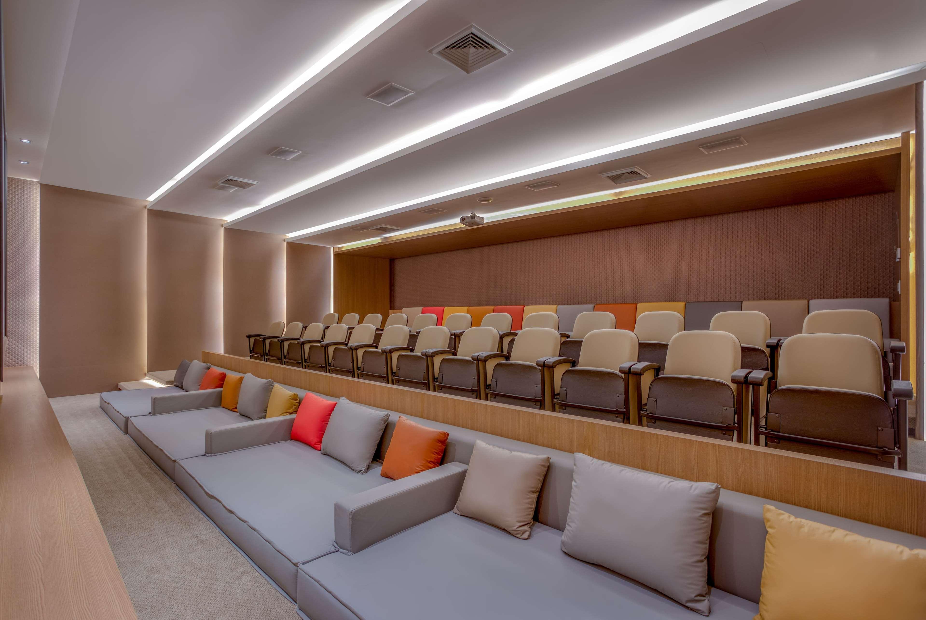 Wyndham Gramado Termas Resort & Spa Exterior foto The photo depicts a modern auditorium or presentation room. It features tiered seating with rows of comfortable chairs and a seating area at the front that has a long sofa with several colorful pillows. The lighting is sleek and ambient, with recesse