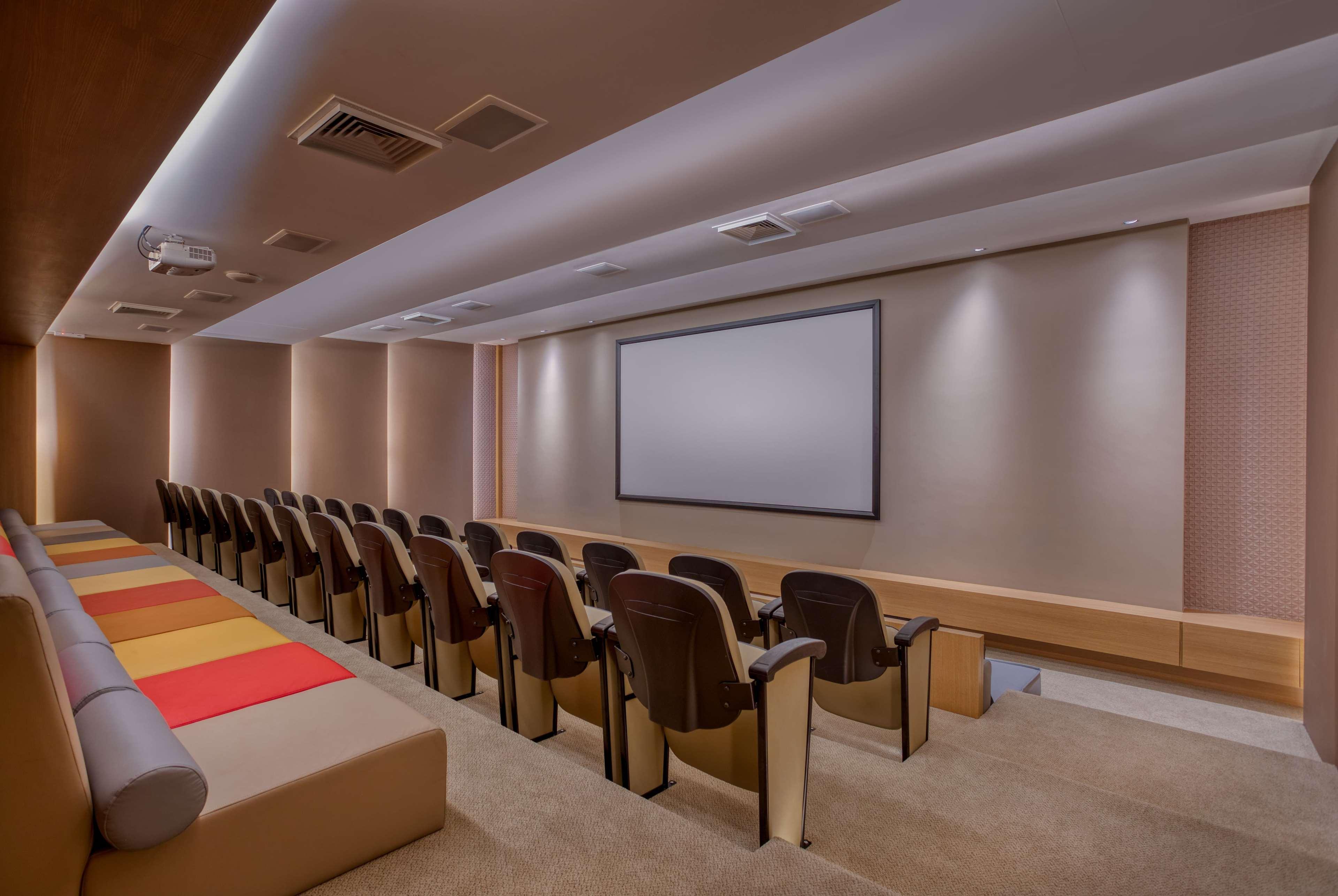 Wyndham Gramado Termas Resort & Spa Exterior foto The image shows a modern and elegantly designed home theater or screening room. It features a row of brown armchairs arranged in a semi-circle facing a large, blank projection screen mounted on the wall. The room has neutral-colored walls with soft l