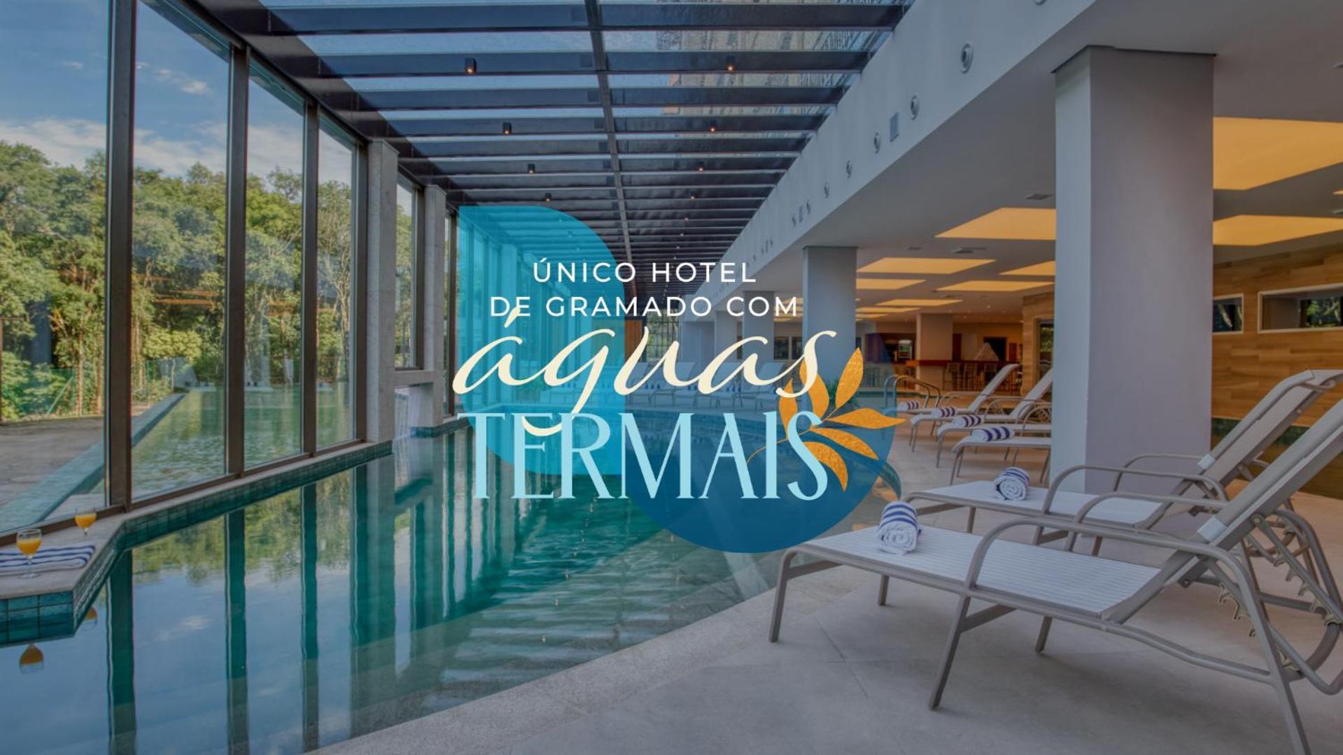 Wyndham Gramado Termas Resort & Spa Exterior foto The photo shows the interior of a hotel featuring a swimming pool, complemented by large glass windows that allow natural light to enter. The setting appears serene and modern, with lounge chairs arranged around the pool area. Text overlay on the ima