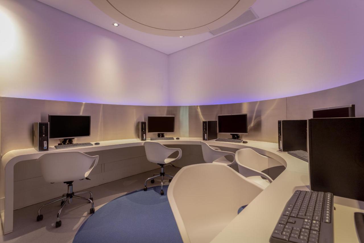Wyndham Gramado Termas Resort & Spa Exterior foto The photo shows a modern, minimalist workspace with several computer stations arranged in a circular layout. Each station features a desktop computer monitor and a keyboard, set against smooth, light-colored walls. The lighting is soft, with a subtle