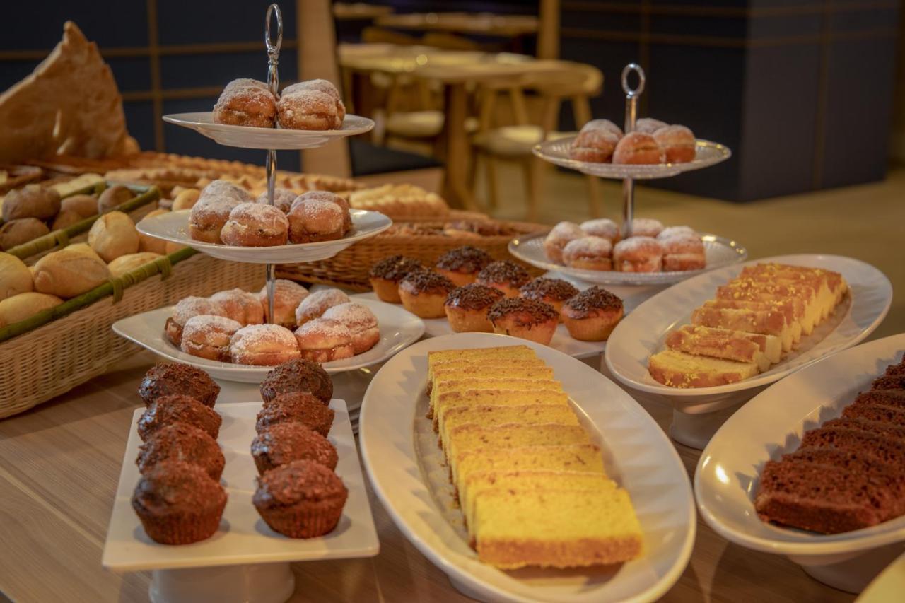 Wyndham Gramado Termas Resort & Spa Exterior foto The photo displays an assortment of baked goods arranged on various plates and stands. In the foreground, there are small chocolate muffins on a plate, alongside a rectangular platter featuring slices of cake. There are also two tiered stands: the to