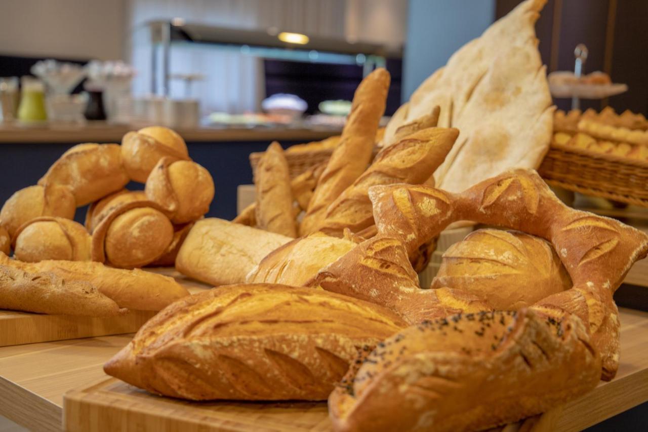 Wyndham Gramado Termas Resort & Spa Exterior foto The photo shows a variety of freshly baked bread displayed on a wooden surface. There are different types of bread, including rolls, baguettes, and loaves, showcasing a range of shapes and textures. Some pieces have a golden crust, while others are s