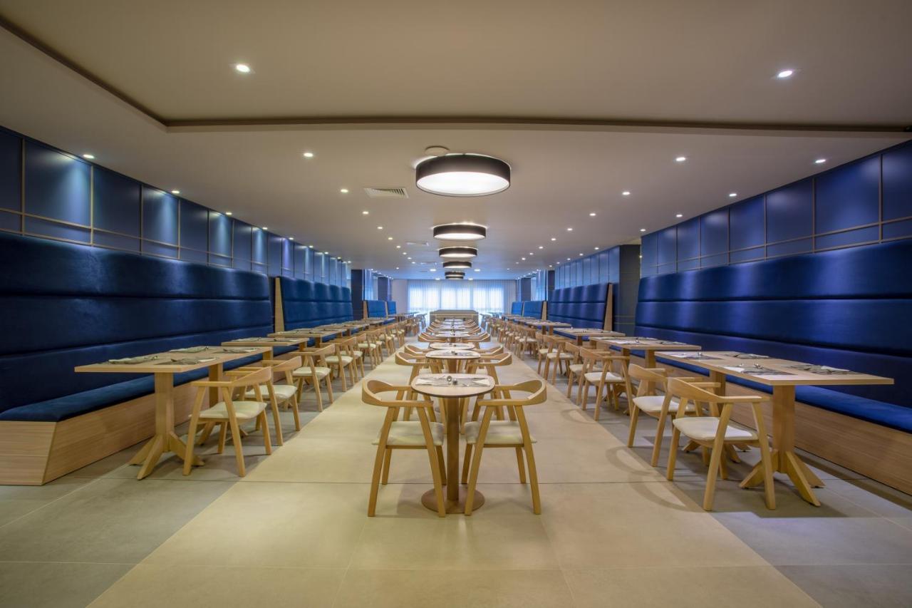 Wyndham Gramado Termas Resort & Spa Exterior foto The photo depicts a modern dining area with a spacious layout. It features a long row of wooden tables arranged neatly across the floor, accompanied by light wooden chairs. The walls are painted in a calming blue tone, and there are recessed lights o
