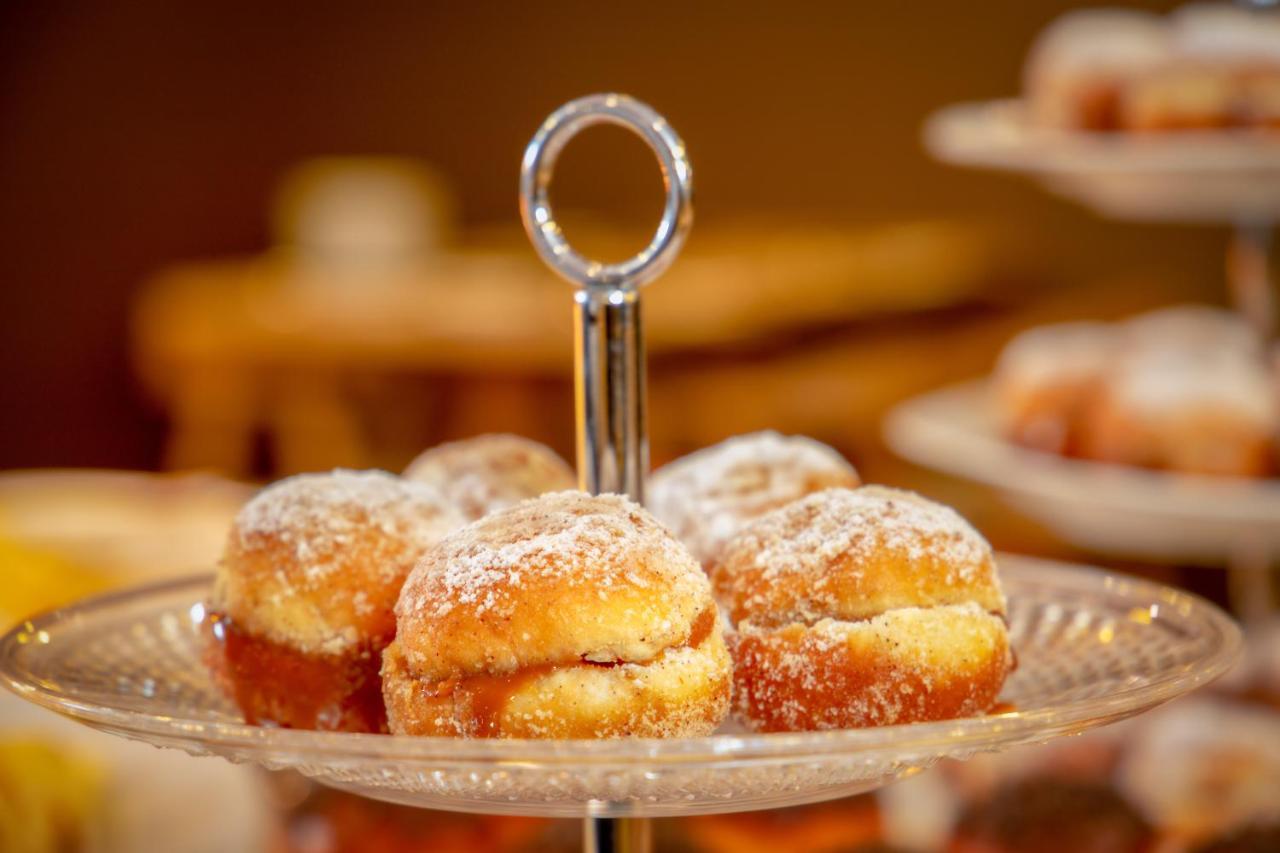 Wyndham Gramado Termas Resort & Spa Exterior foto The photo shows a tiered serving dish featuring several small, round pastries. The pastries appear to be doughnuts or similar baked goods, dusted with powdered sugar. They are filled with a sweet filling, likely jam or cream, visible in the middle wh