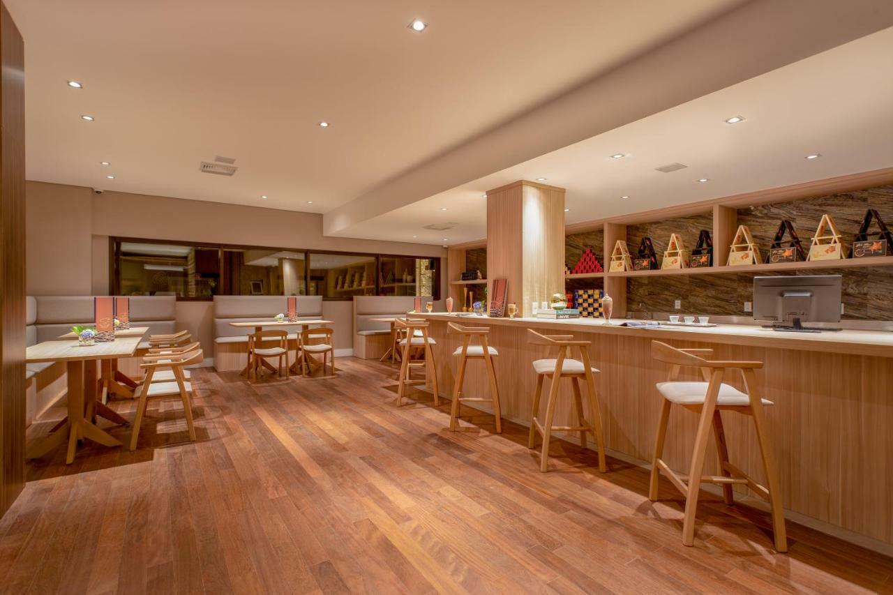 Wyndham Gramado Termas Resort & Spa Exterior foto The photo shows a modern and inviting interior of a bar or restaurant. It features wooden flooring and a warm ambiance, created by soft lighting. On one side, there is a bar area with high stools and a counter, with shelves displaying various bottles